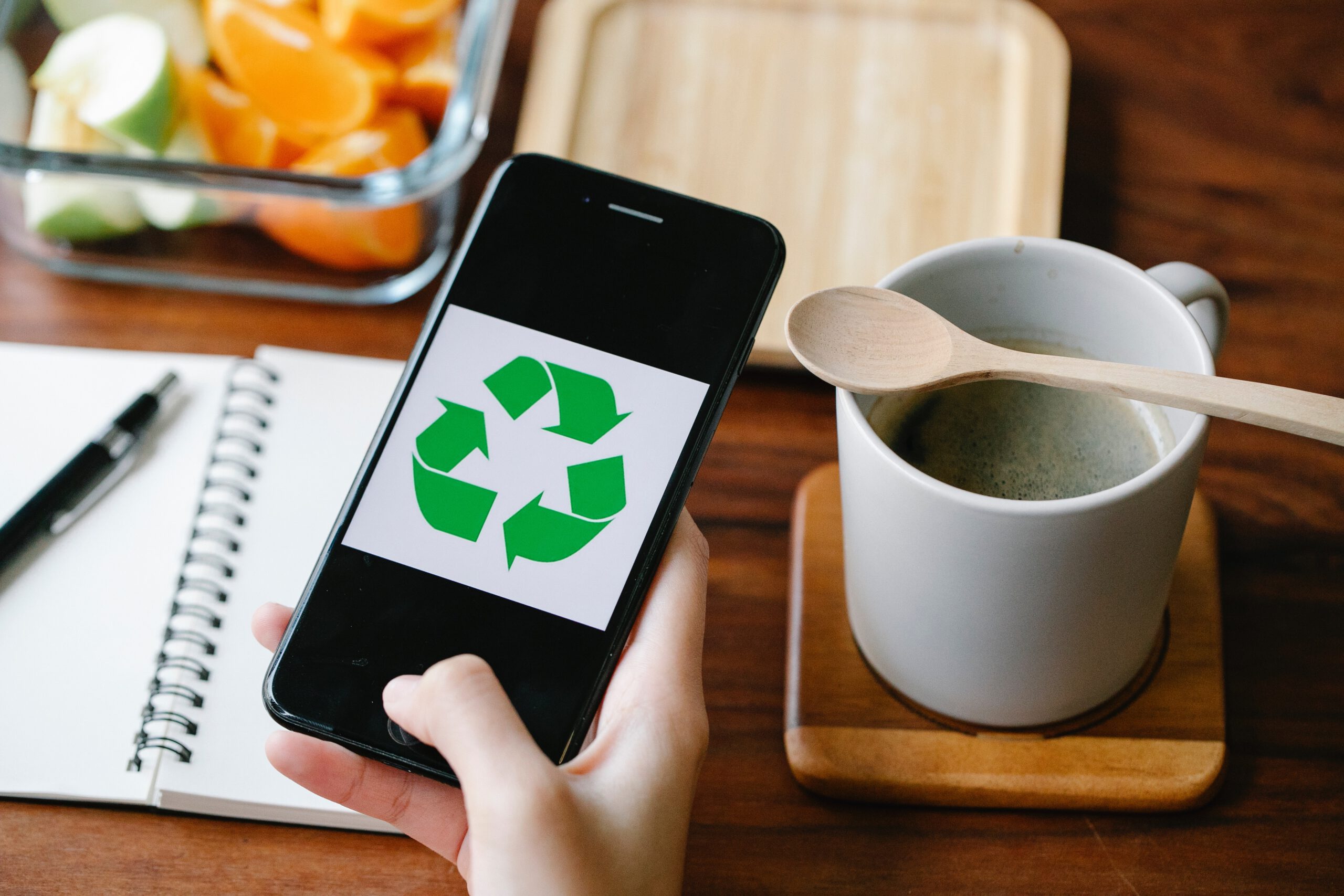 Een ecologisch bewuste persoon die een smartphone vasthoudt met een recycle-symbool erop.