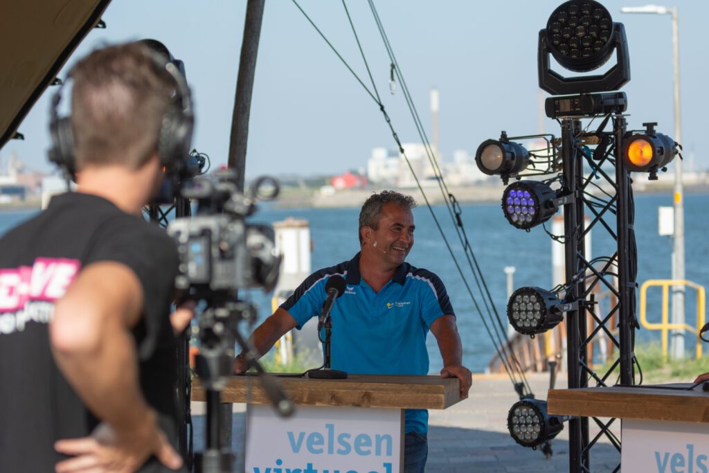 Voor een podium staat een man met een ecologische trofee.